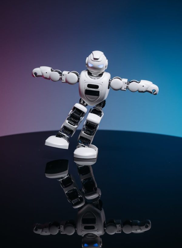 A white robot toy posed dynamically on a glossy reflective surface with a gradient background.