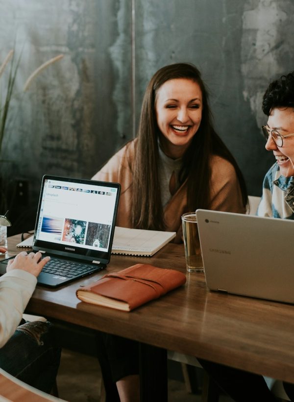 three people sitting in front of table laughing together